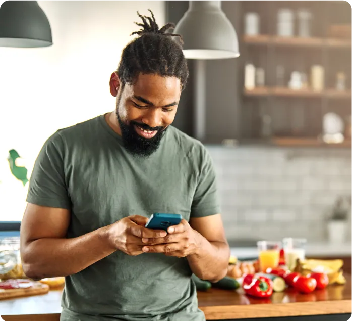 A man holding a cell phone with a smile on his face.