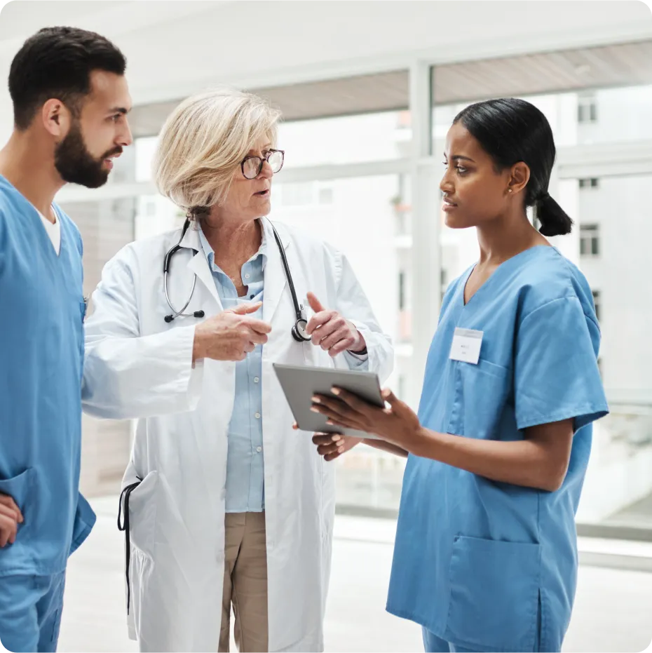 A woman in a white coat is showing a tablet to a man and a woman.