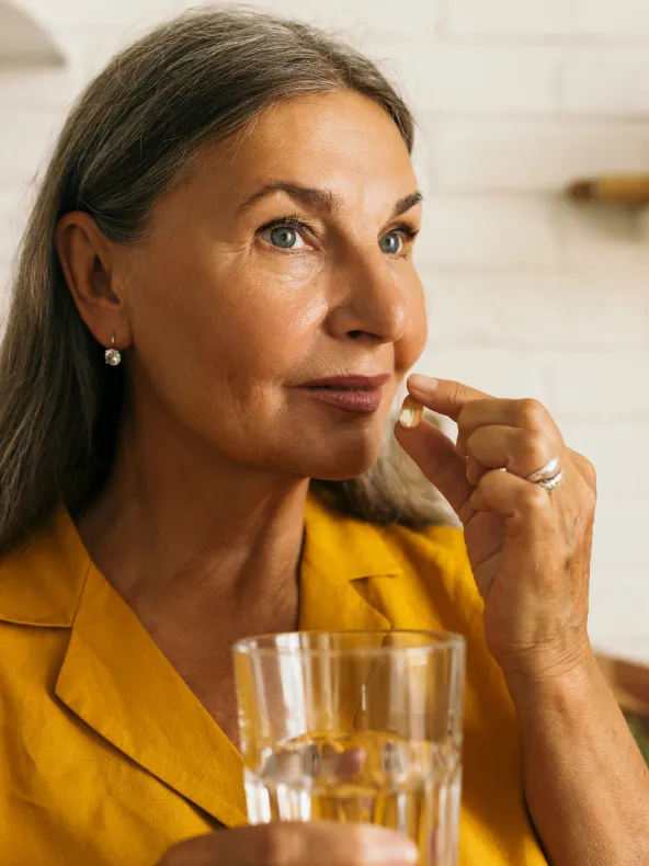 A woman in a yellow shirt is holding a glass of water.
