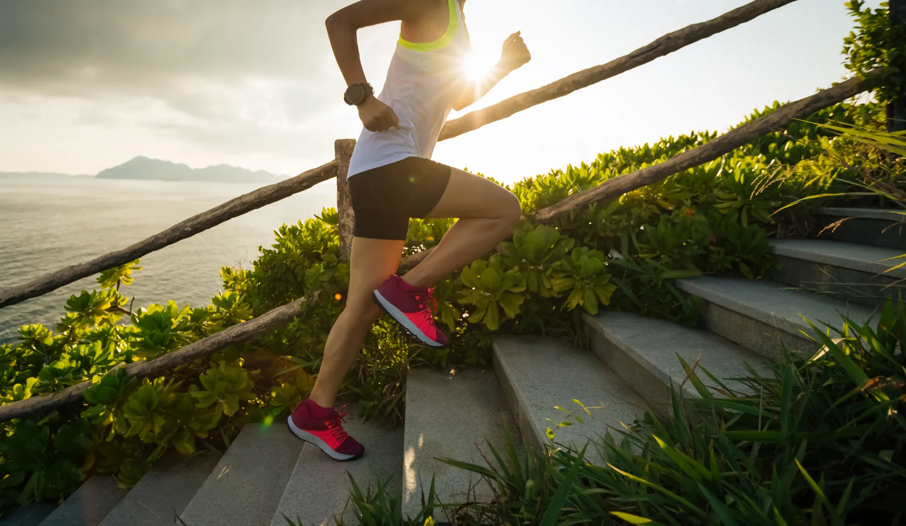 A woman running down a set of stairs with a beautiful view of the ocean.