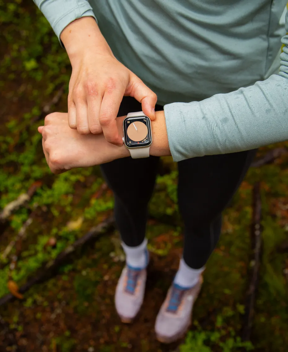 A woman wearing an apple watch with a blue shirt and black pants.
