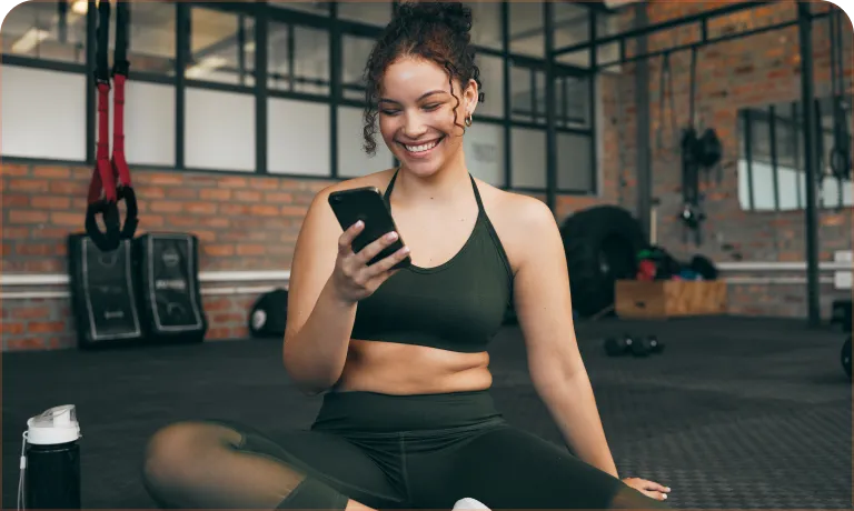 A woman sitting on the floor holding a cell phone.