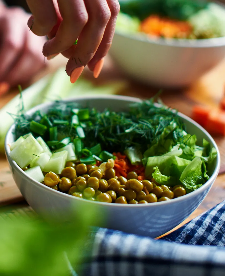 A white bowl filled with vegetables and herbs.
