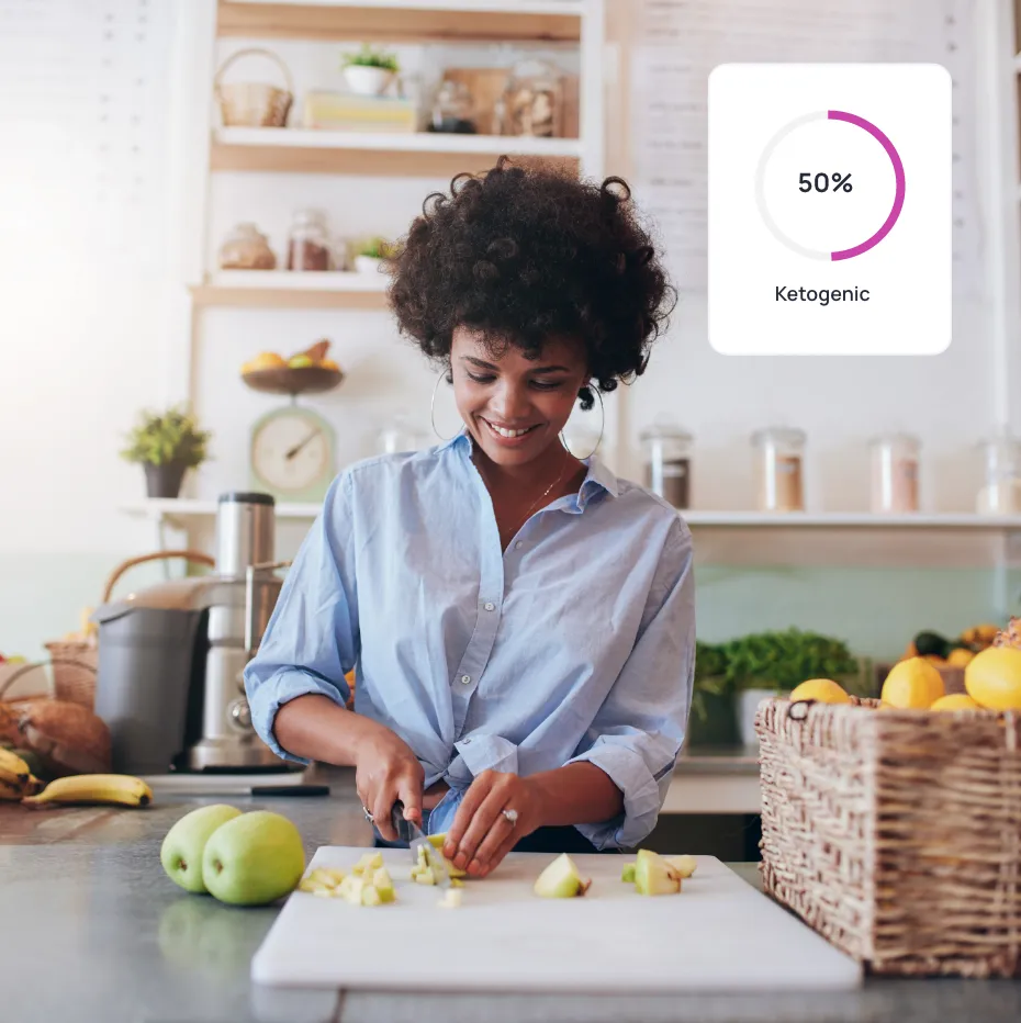 A woman cutting fruit in a kitchen with a nutrient value from Cronometer on it.