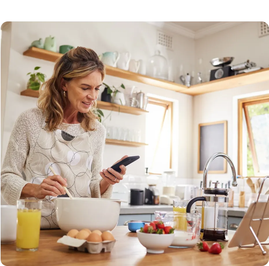 A woman in a kitchen holding a cell phone.