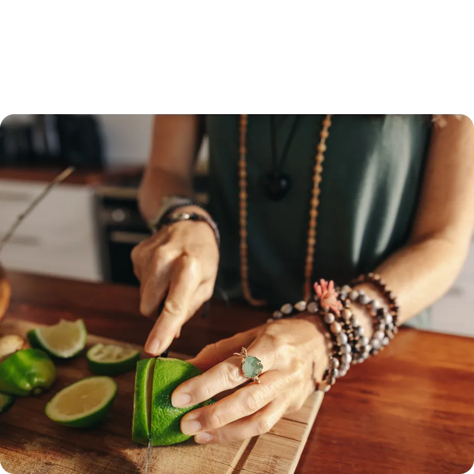 A woman is cutting a lime on a cutting board.
