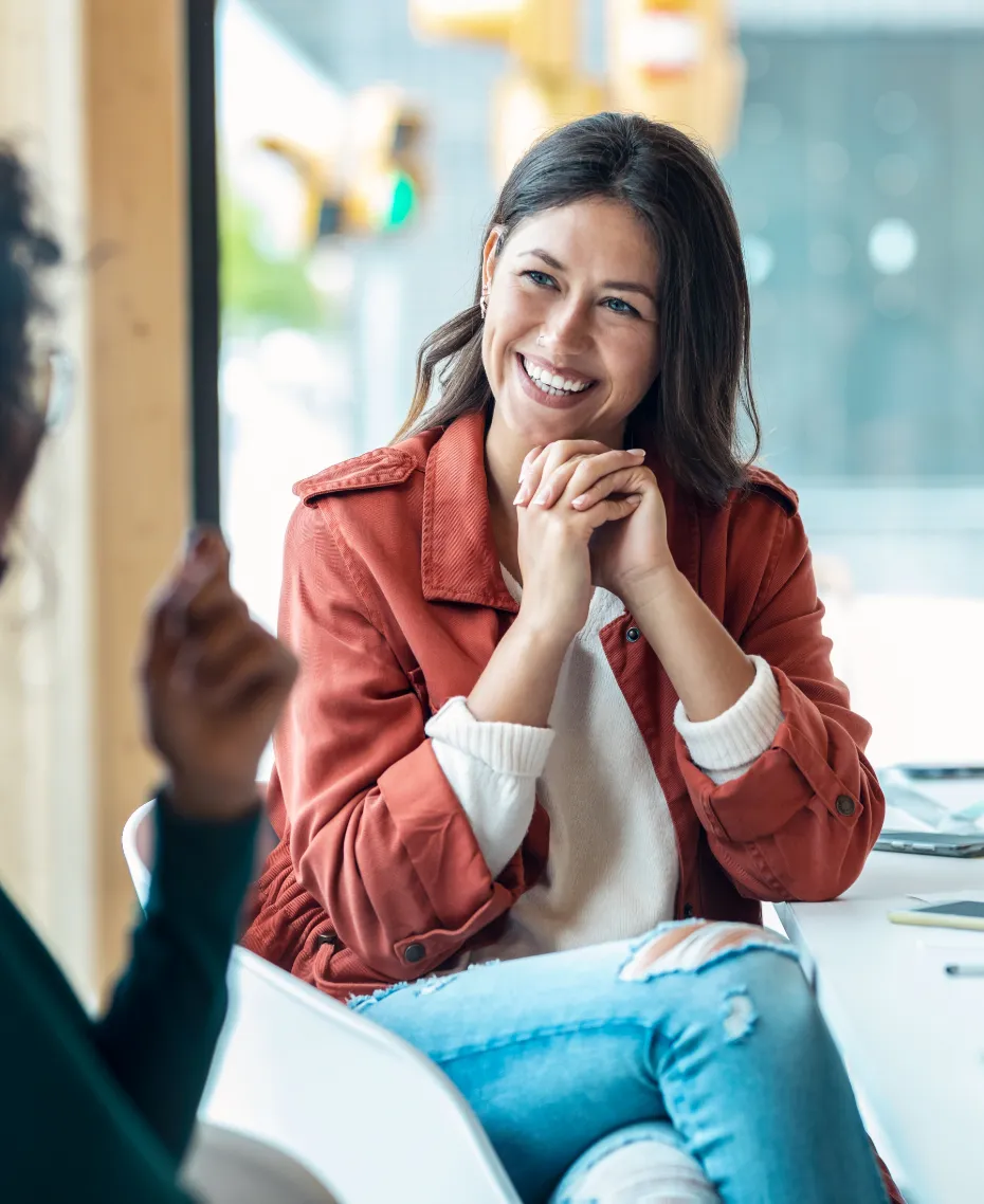 A woman wearing a red jacket and blue jeans.