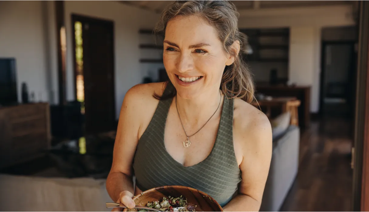 A woman in a grey tank top smiling at the camera.