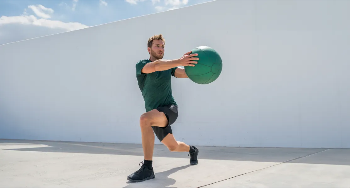 A man in a green shirt and black shorts is holding a green ball.