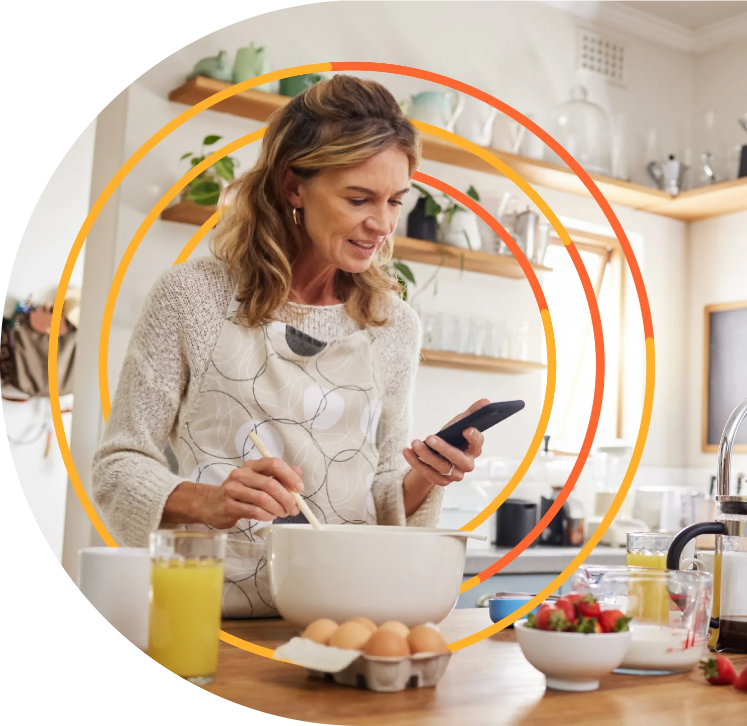 A woman in a kitchen holding a cell phone.