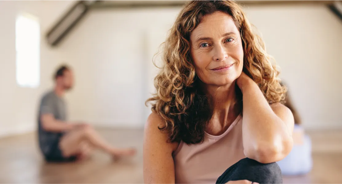 A woman with long hair and a pink shirt is sitting on the floor.